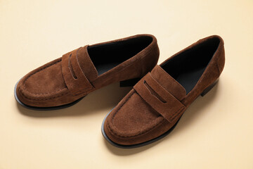 Pair of stylish chamois leather shoes on beige background