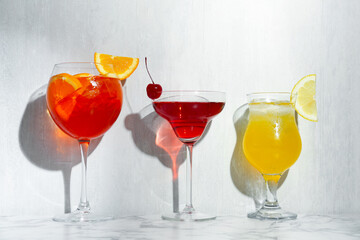 Glasses of tasty cocktails with garnish on white marble table