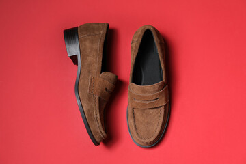 Pair of stylish brown shoes on red background, flat lay