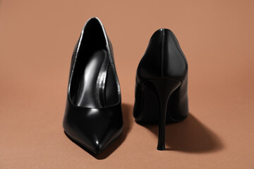 Pair of stylish high heeled shoes on brown background, closeup