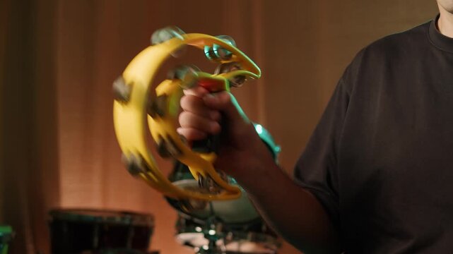 Musical instrument, tambourine Percussion, man playing in studio, sound and creativity. Plastic tambourine in a mans hand.