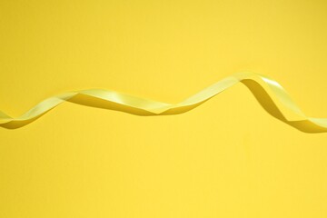 Beautiful ribbon on yellow background, top view