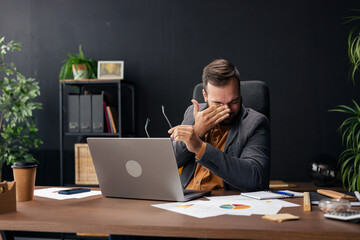 Businessman suffering from eye strain and headache at work