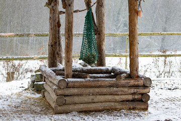 ein grünes fast leeres Heunetz hängt über einer Holz Raufe aus Lärchenholz Baumstämmen an...