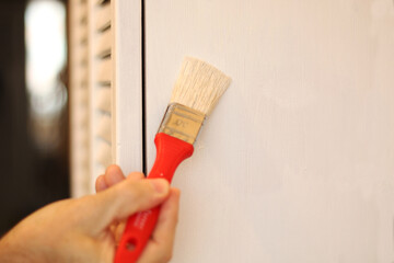 A man paints an old cabinet with a brush.