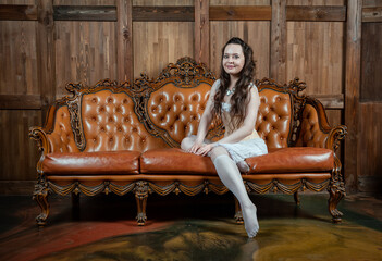 Beautiful sensual woman wears vintage underwear sitting on the brown leather sofa