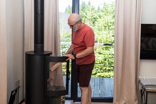 Man at home preparing a wood stove for a cozy evening