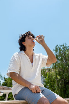 Young man drinking water during a hot summer day
