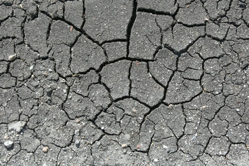 Dried cracked pavement surface in a construction zone, broken apart over time due to heat and wear.,