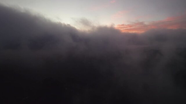 Soaring through thick, dark clouds during a vibrant sunset over the Canary Islands from an aerial view