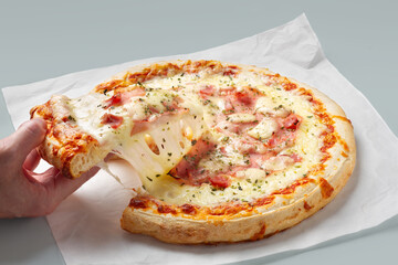 Hand holding a slice of freshly baked pizza