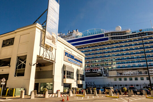Boston, MA - US - Oct 2, 2025 A large cruise ship is docked at the Flynn Cruiseport terminal, with a building and a banner visible in the foreground.