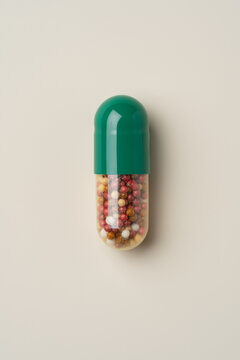Top view of a colorful pill with green top on beige background