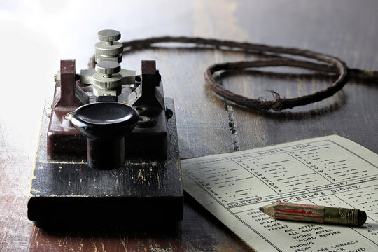 morse key with morse code chart on desk