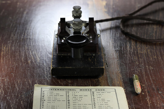 morse key with morse code chart on desk