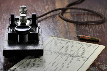 morse key with morse code chart on desk
