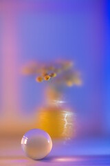 Crystal ball reflecting tansy flowers against a blue-orange gradient background, capturing the serene and ethereal mood on a glass surface