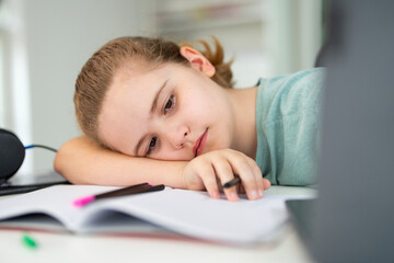 Kid reading books and writing homework in home school environment. Homeschool education helping children gain digital knowledge. Kid using laptop for interactive home school and knowledge growth.