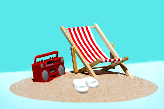 Deck chair and radio on sandy beach with blue sky