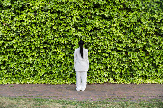 Businesswoman in a white suit among urban greenery
