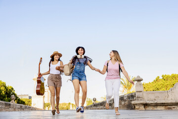 Multicultural friends laughing and holding hands outdoors, symbol of unity and joy