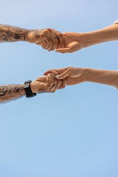 Couple holding hands against clear blue sky