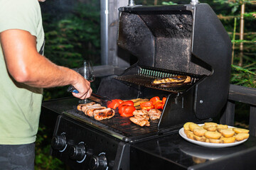 Man grilling dinner on an electric barbecue outside