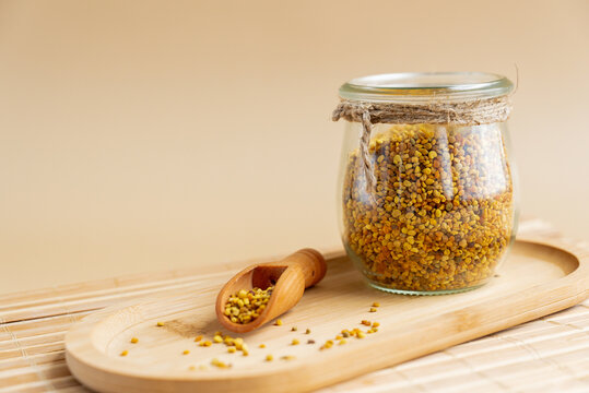 Natural bee pollen in a glass jar with wooden scoop