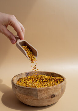 Organic bee pollen in wooden scoop with beige background