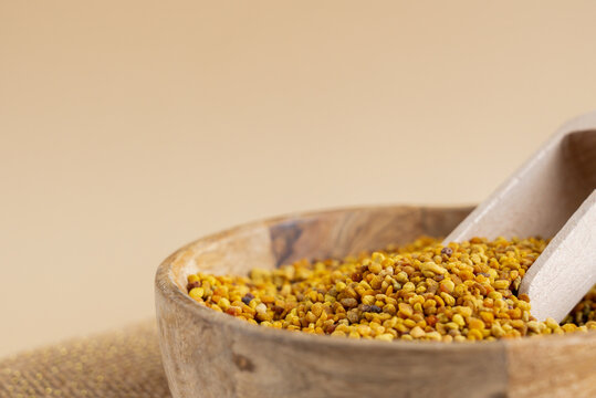 Bee pollen in a wooden bowl on beige background