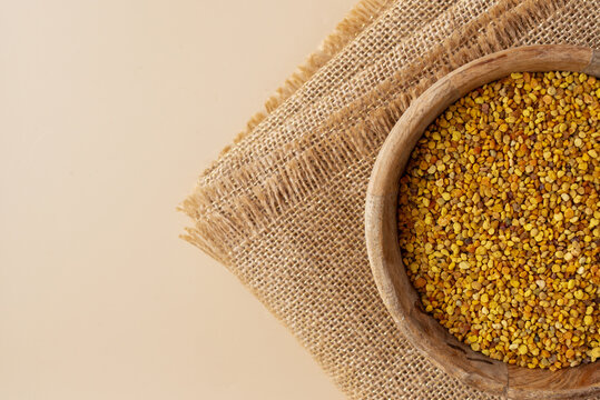 Top view of bee pollen in a wooden bowl on burlap
