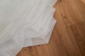 White transparent fabric on a background of light wood with sun rays.