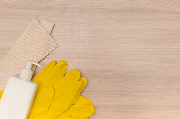 Yellow rubber gloves on wooden tabletop, microfiber cleaning cloth.