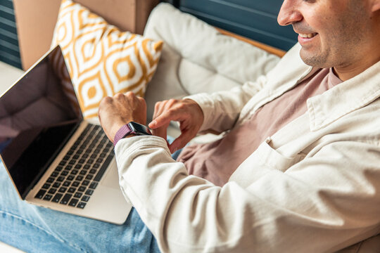 Hispanic man teleworking at home checking smartwatch