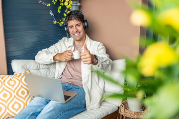 Young Hispanic man teleworking from home giving thumbs up