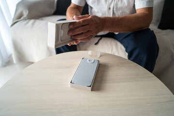 Elderly man unboxing smartphone designed for seniors