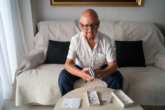 Elderly man unboxing new smartphone designed for seniors