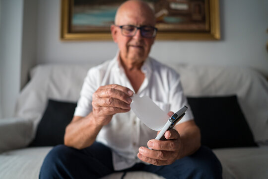 Elderly man unboxing a smartphone designed for seniors