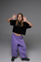 Young caucasian teen girl posing playfully in black top and purple pants