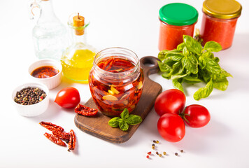 Dried organic tomatoes preservation with herbs and olive oil in jar.