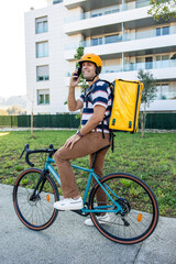 vertical Hispanic delivery man on bicycle talking on smartphone