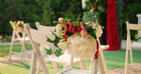 Special ceremony outside decor in red colour theme. Wooden chairs and red flowers at the restaurant.