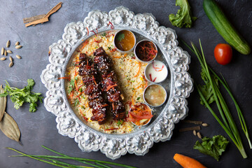 Chicken Shashlik Skewers with Vegetable Rice and Dips on a Silver Platter top view of bangladeshi food