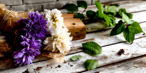 Fototapeta premium A bouquet of fresh purple and white dahlia flowers rests on a rustic white wooden surface.