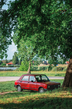 Red Stojadin Zastava 101 Skala 55-65 (Fiat 128 related) parked under tree summer day. Atmosphere of rural serenity, unhurried peace, Polako Balkan lifestyle. Palic, Serbia. June 03, 2025.