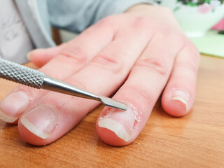 A woman smooths her finger cuticles with a nail file, manicure. Cosmetic care, preparation for a manicure.