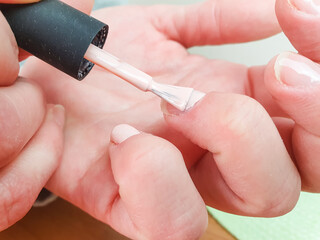 A woman applies nail polish to her fingernails, close-up. Manicure procedure. Nail care, finger care, cosmetic care.