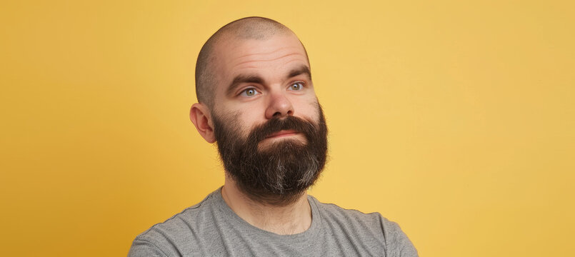 Casual Man with Beard and Shaved Head Against Yellow Background