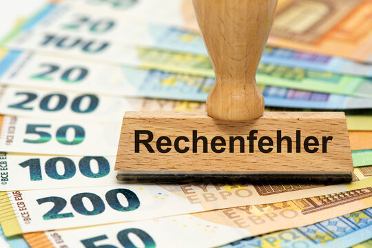 Ein Holzstempel ist beschriftet mit dem Aufdruck Rechenfehler auf vielen Euro Banknoten als Symbolbild f&uuml;r eine Falschberechnung in den Finanzen