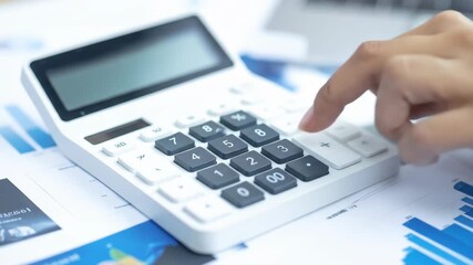 Close-up of a hand operating a calculator on a desk with financial documents and a laptop, calculating data - Powered by Adobe
